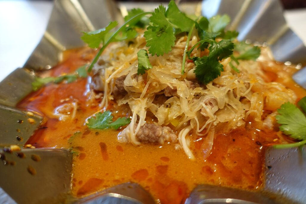 Finely shredded green cabbage heaped in a large bowl beside a knife and half a head