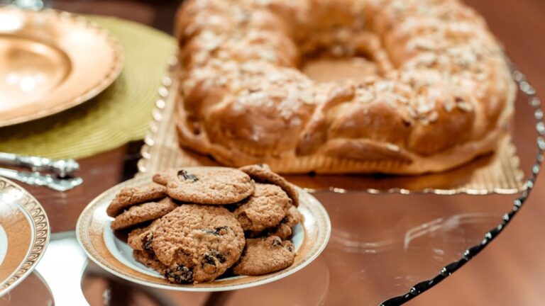 A close-up of a batch of perfectly baked chocolate chip cookies with golden edges and soft centers, alongside a few flat, overspread cookies on a parchment-lined baking sheet, illustrating common baking problems and successful outcomes.