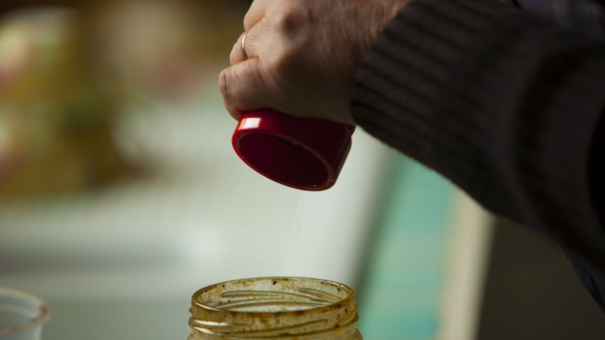 A variety of colorful canned and pickled fruits and vegetables displayed on a rustic wooden shelf.