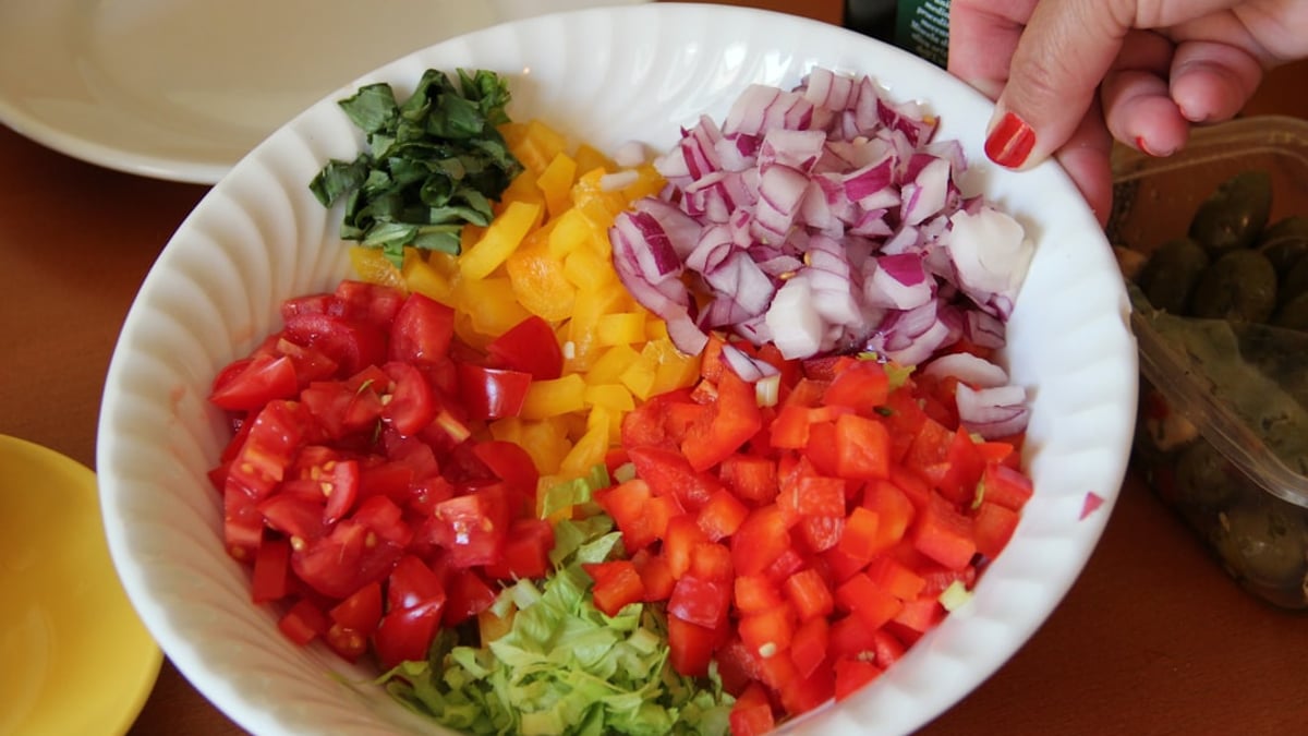 Close-up of a chef demonstrating proper knife skills, dicing an onion with a sharp chef's knife on a wooden cutting board.