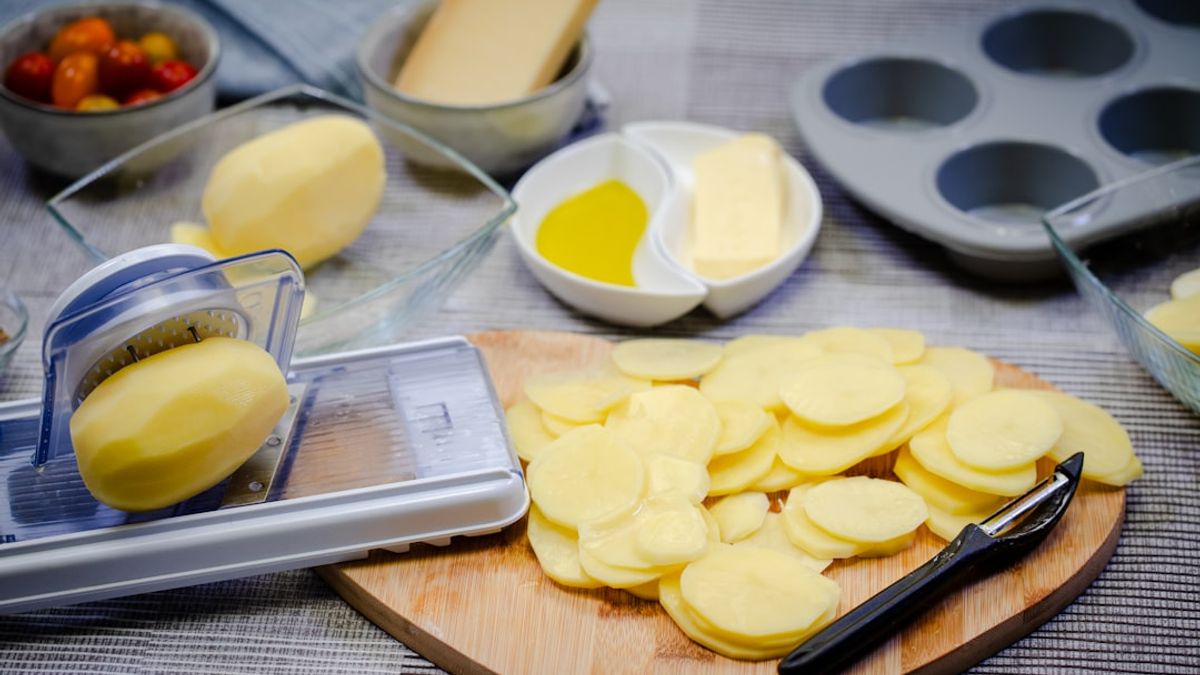Overhead shot of various colorful, portioned batch-cooked meals in glass containers on a wooden kitchen counter, with fresh i...