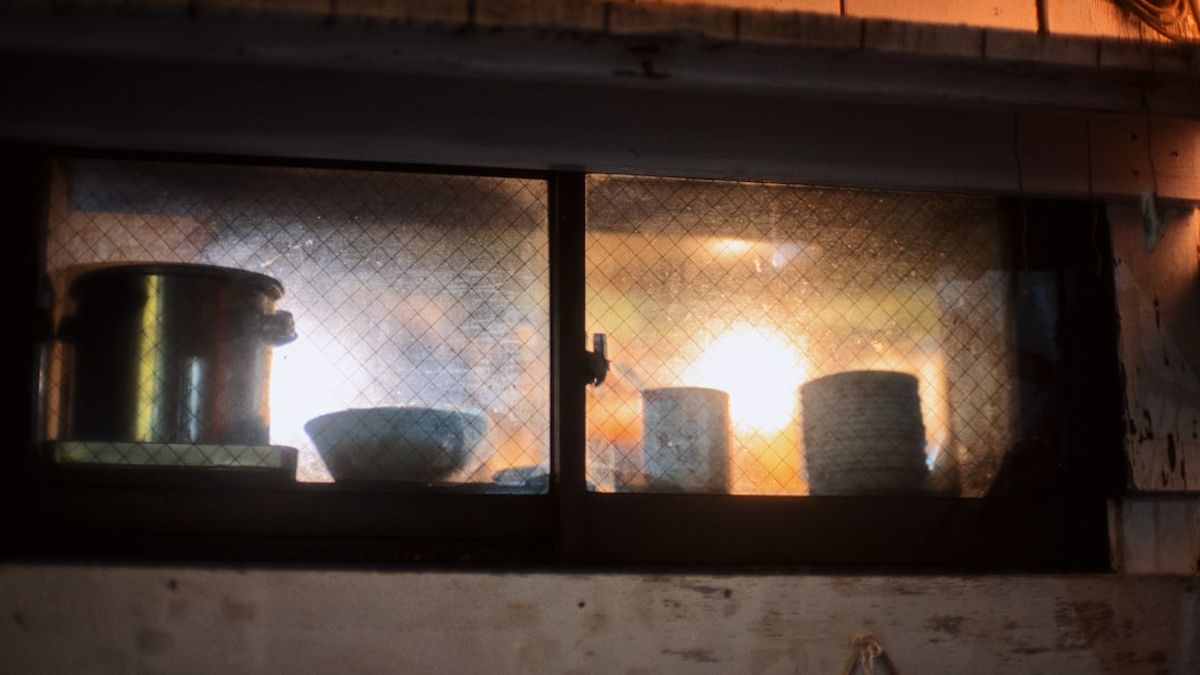 Young couple batch cooking beans and chicken stew in a small apartment kitchen, storing food in glass containers – Americans cooking 2026