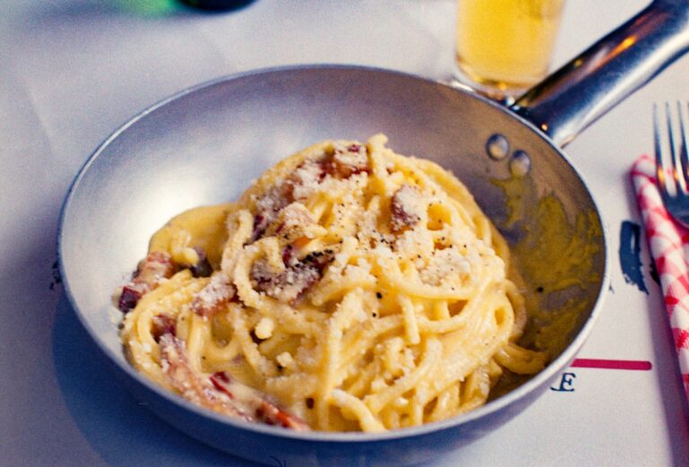 Plate of spaghetti carbonara with crispy guanciale and freshly cracked black pepper