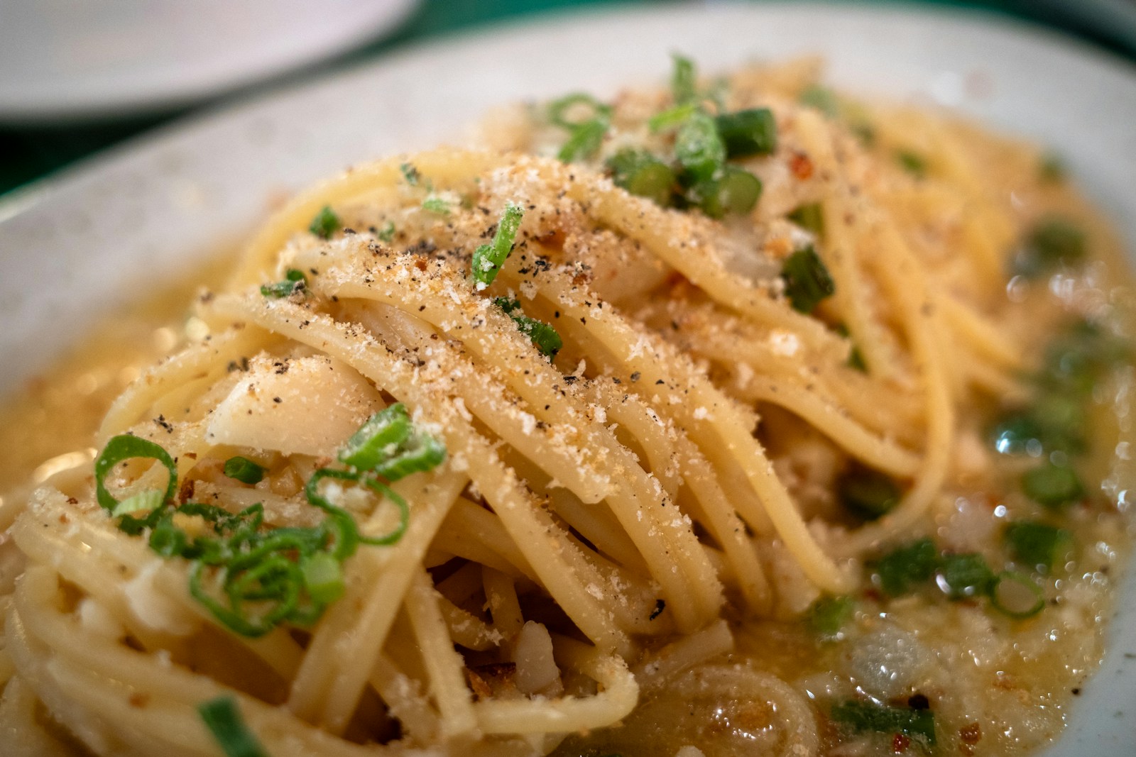 Close-up of strands of pasta coated in glossy pecorino cheese sauce with cracked black pepper