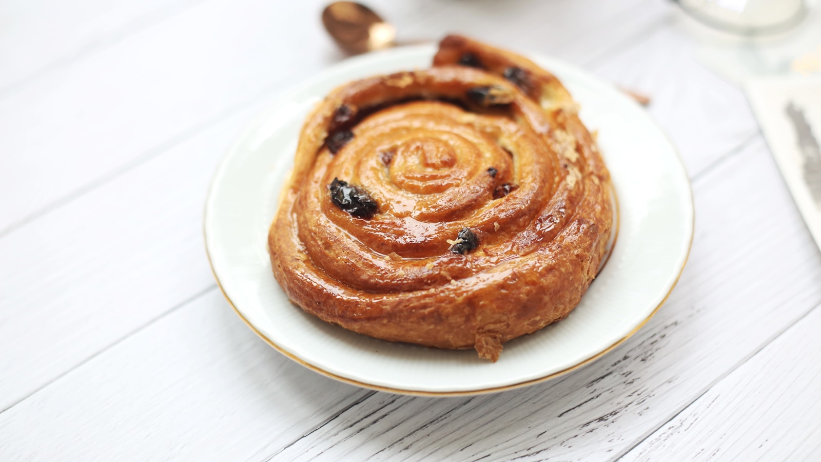 Twisted Swedish cardamom buns on baking paper with pearl sugar scattered on top