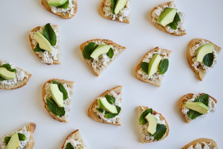 Whipped feta crostini topped with vibrant green peas, fresh mint leaves, and lemon zest arranged on a rustic wooden serving board