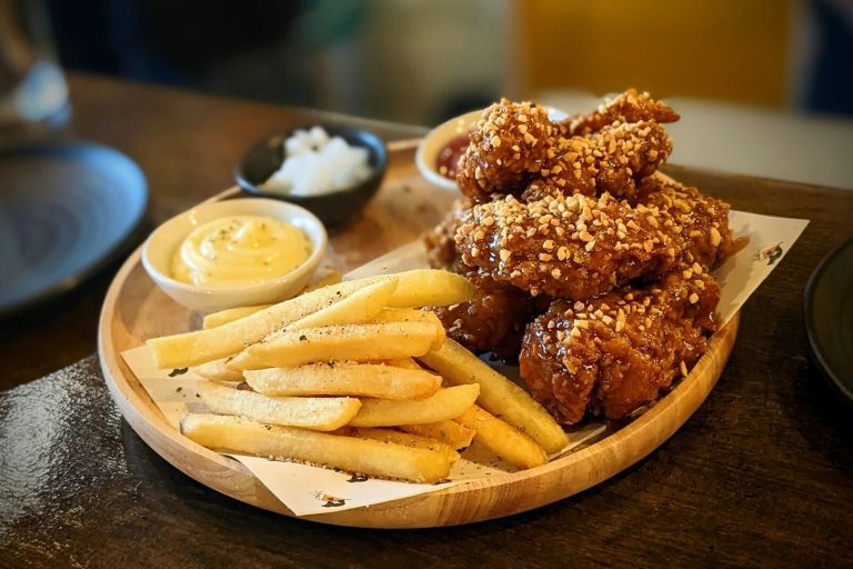 Double-fried Korean chicken with sesame coating on wooden board