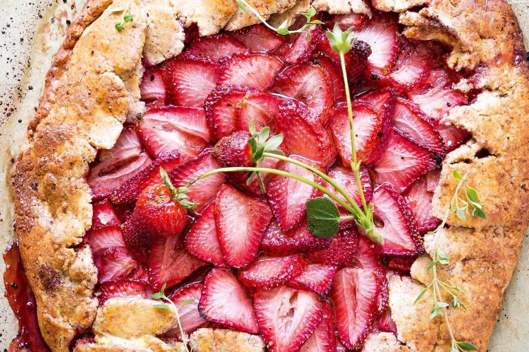 Free-form strawberry galette with rustic folded crust on parchment