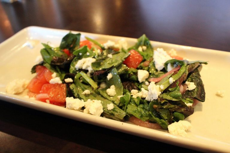 Watermelon feta salad with mint, red onion, and olive oil on a white platter