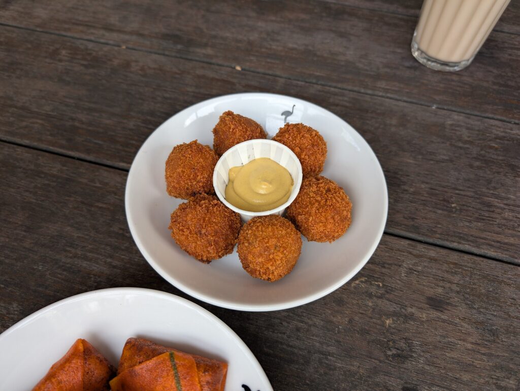 An open jar of smooth mustard with a small spoon resting on the rim