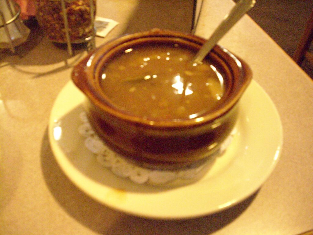 A pot of vegetable and bean soup simmering with a ladle resting against the rim
