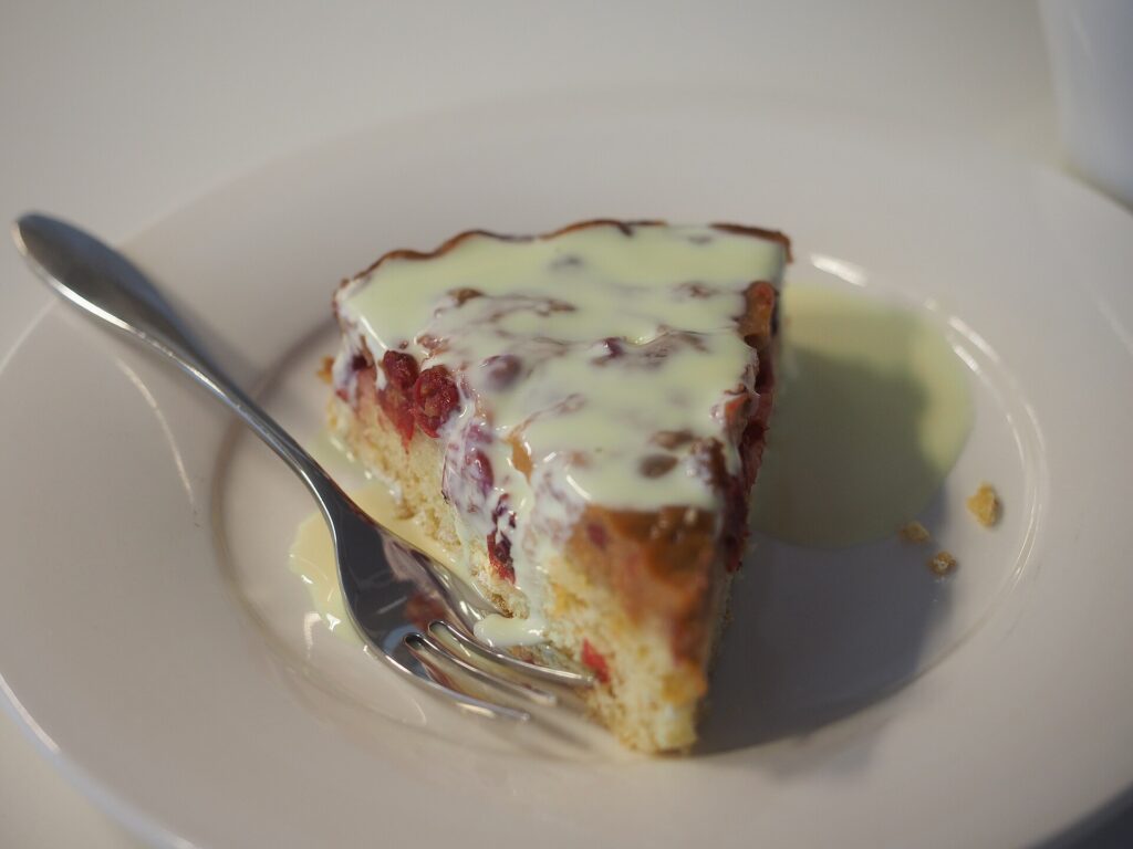 A slice of set custard pie on a plate with the pastry edge visible