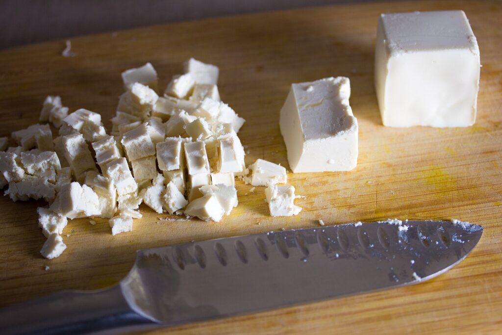Cubes of cold butter in a small white bowl beside a whisk