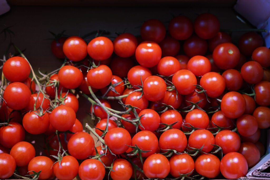 A wooden crate packed with deep red plum tomatoes on a market table