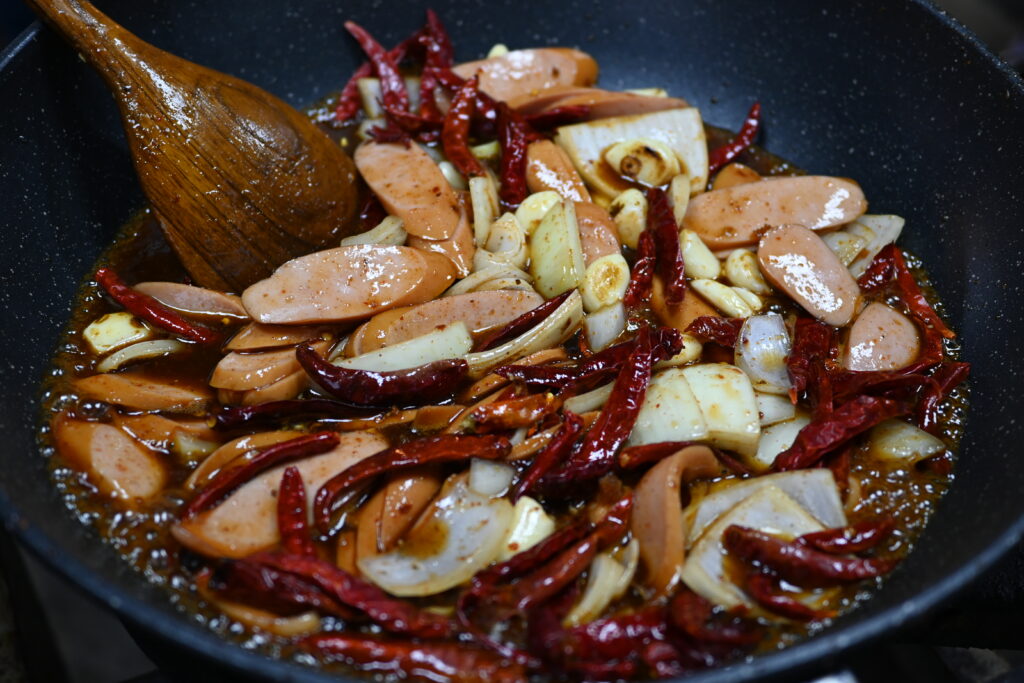 Whole dried red chiles spread across a metal tray beside a small strainer