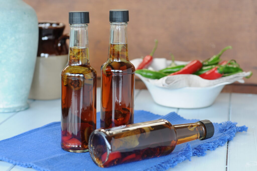 Several bottles of vinegar lined up on a kitchen shelf in afternoon light