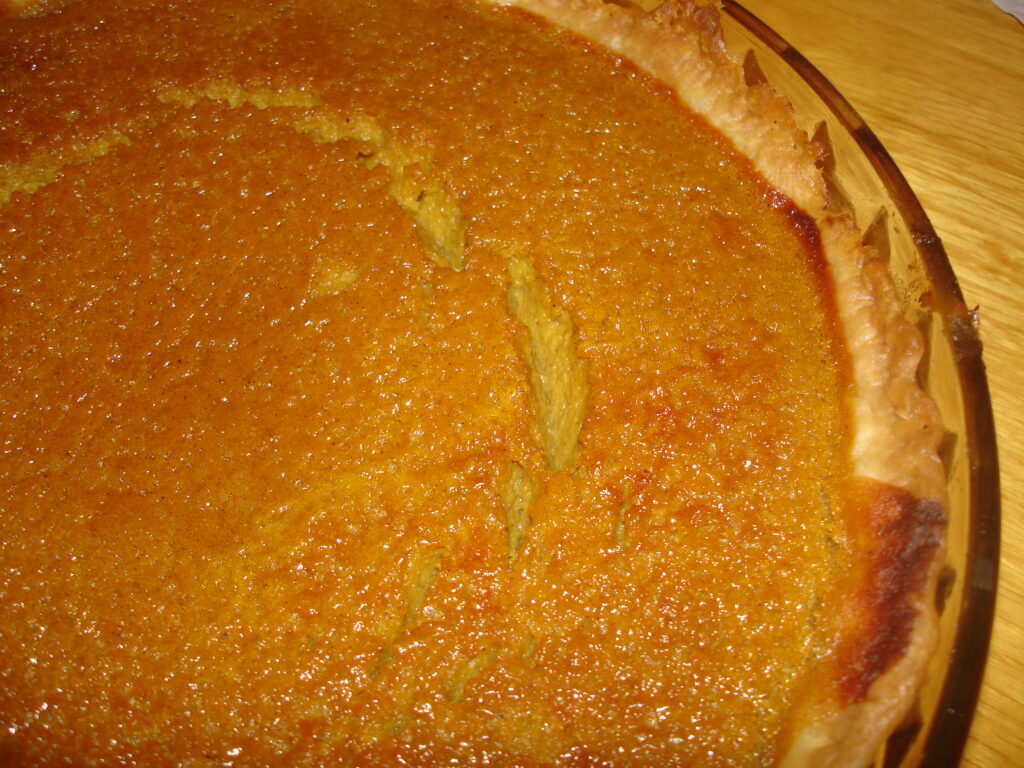 A clear glass pie dish holding a pale baked shell seen from the side