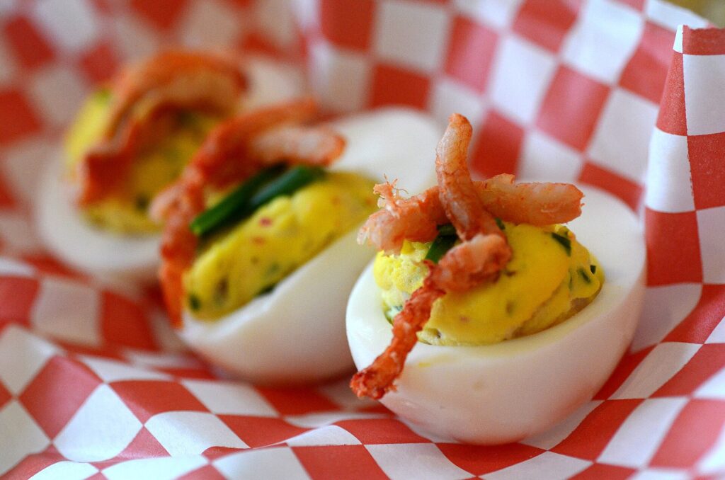 A tray of deviled eggs nested in crushed ice on a serving table