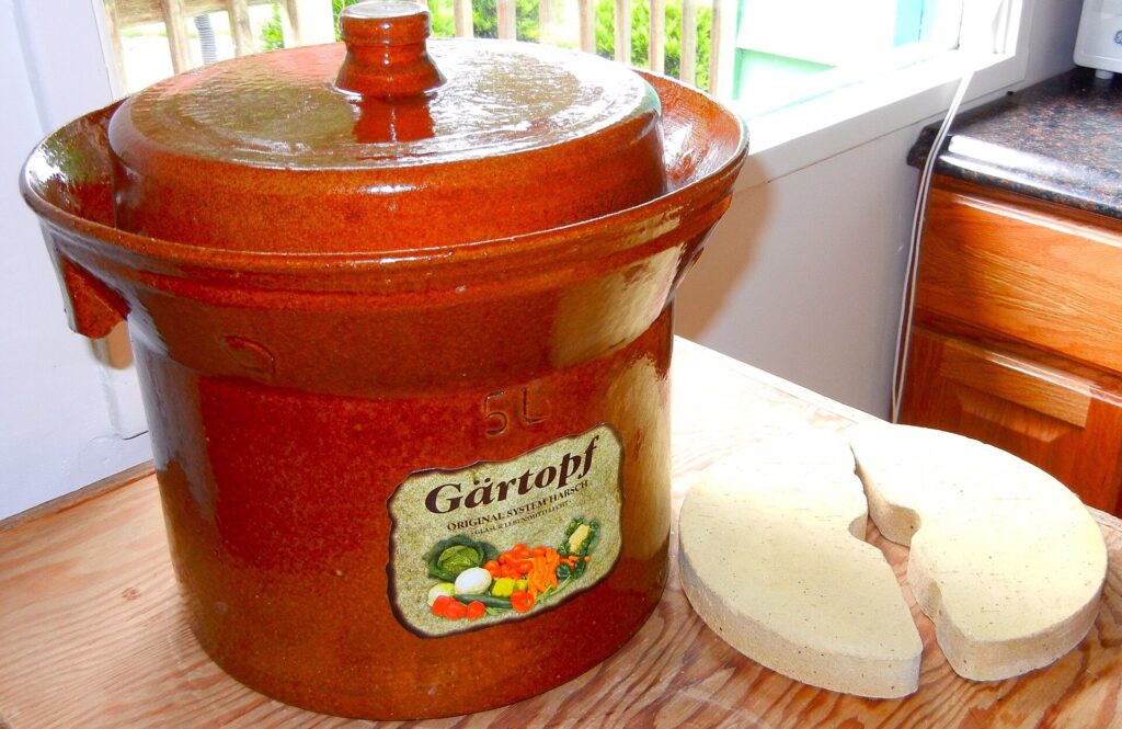 A stoneware crock with its lid off showing two ceramic weights resting inside