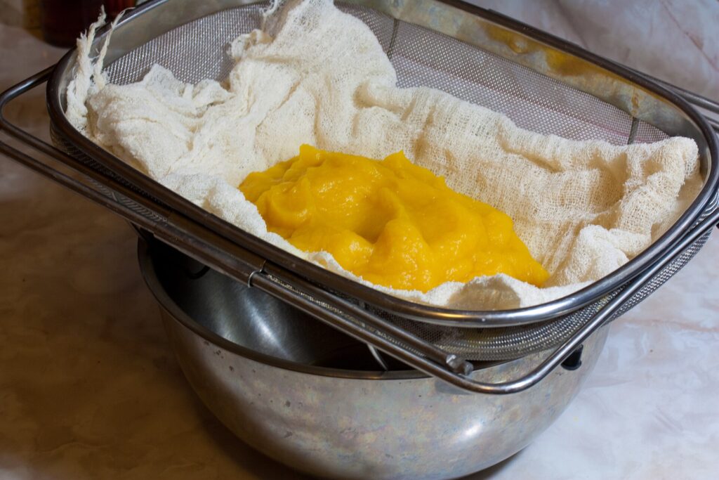 Smooth orange pumpkin puree in a white bowl with a spatula resting against the rim