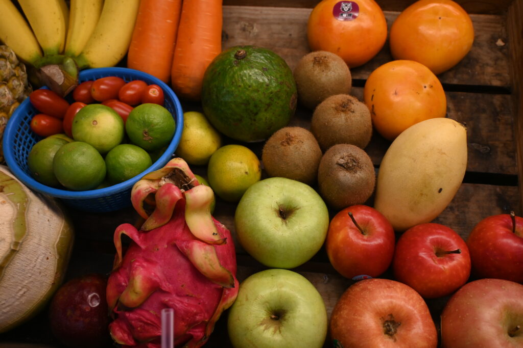 Red and green apples heaped in a wooden orchard crate on wet grass