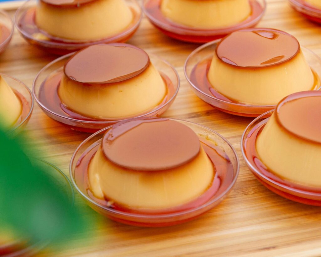 Thick golden caramel sauce being poured from a pan into a small glass jar