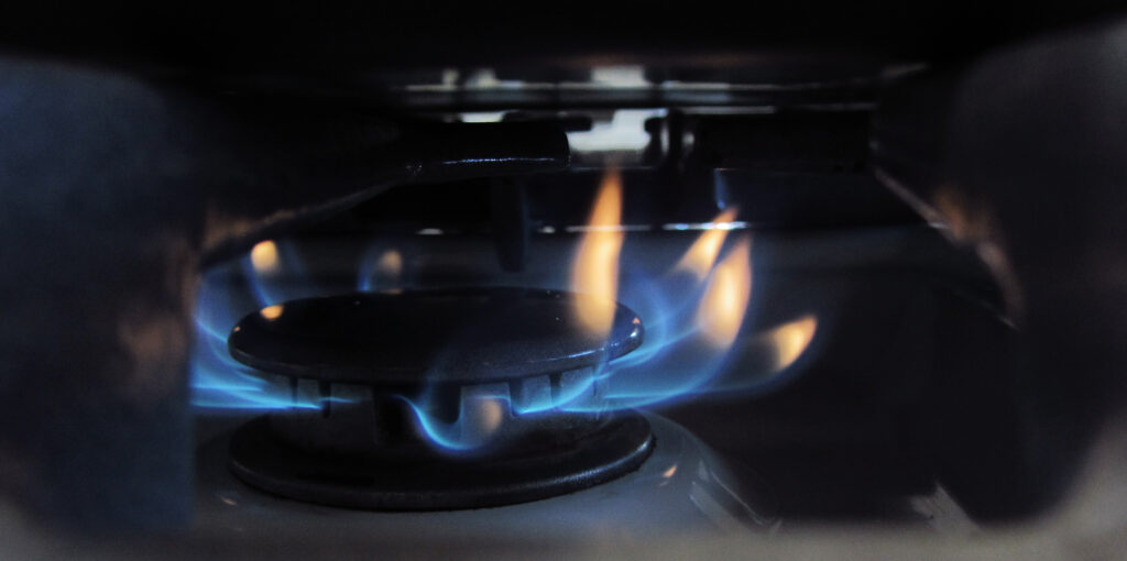 A blue gas flame under the base of a heavy pot on a domestic stove