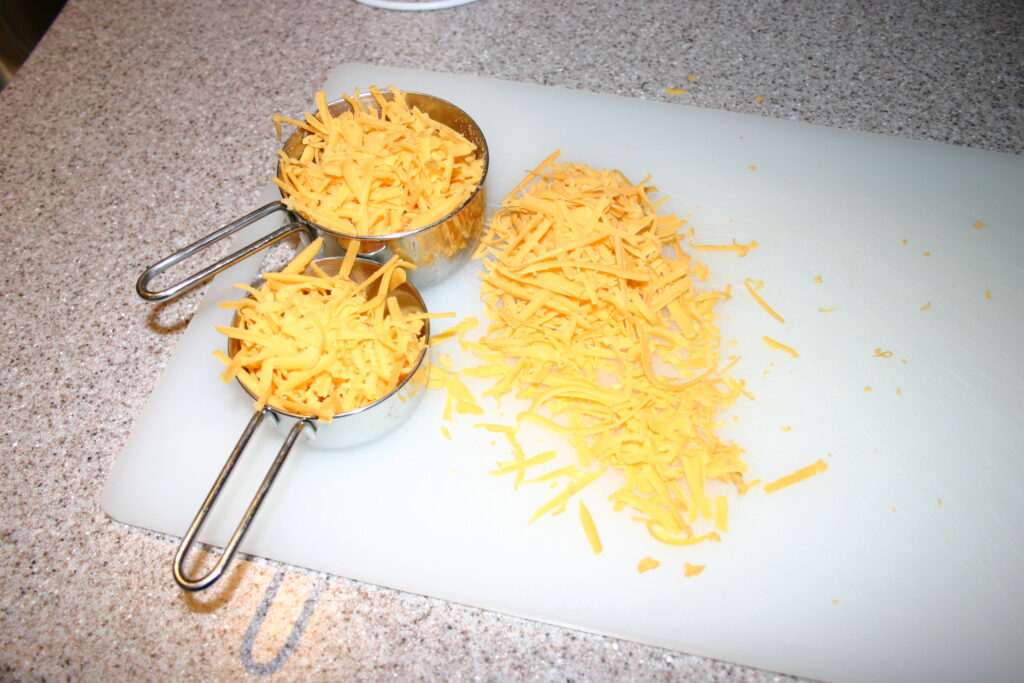 A bowl of buttered pasta with fine shavings and coarse black pepper across the top