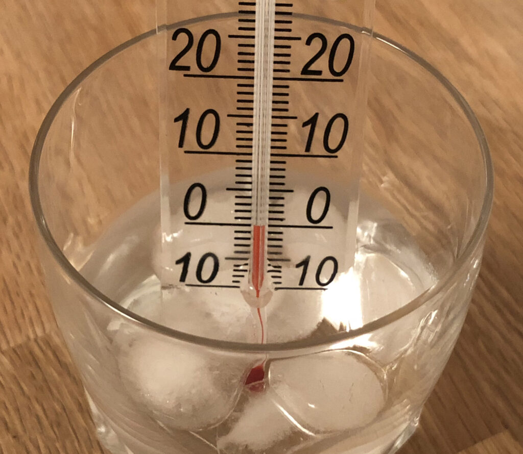 Granulated sugar half melted in a wide pan with pale amber patches forming