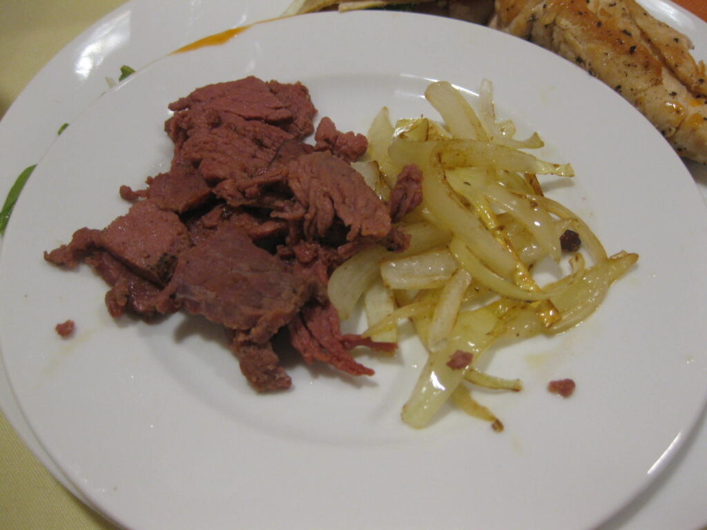 A large browned beef roast being carved into thick slices with a long knife