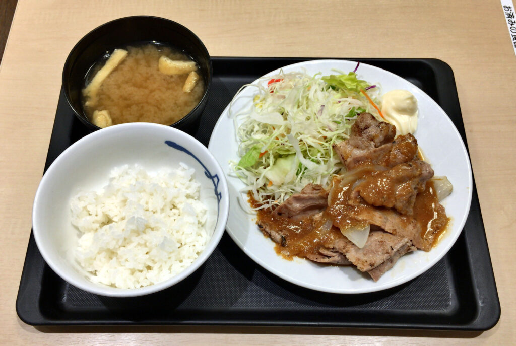 Thick pieces of pork shoulder browning in a hot cast iron pot with visible crust