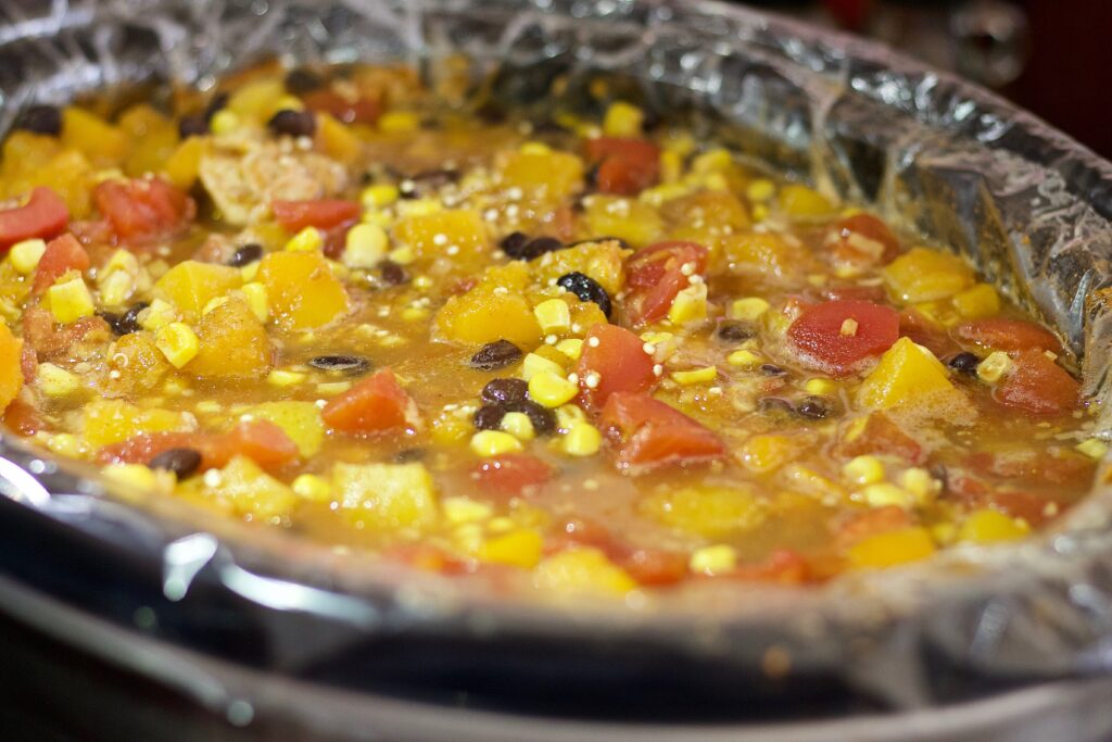 A large slow cooker filled with amber cider and floating orange slices