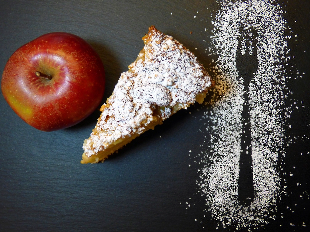 A cut slice of double crust apple pie showing distinct fruit wedges inside