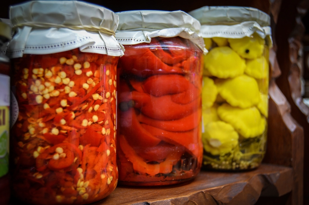 A sealed glass jar of kimchi on a kitchen counter with brine bubbling near the lid