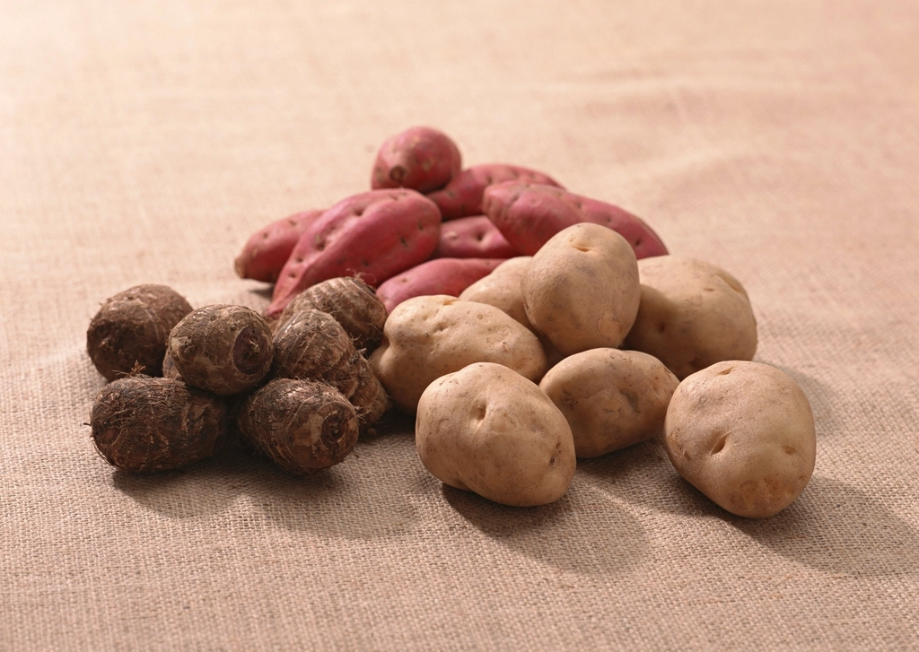 Loose potatoes spilling from an open burlap sack onto a wooden floor