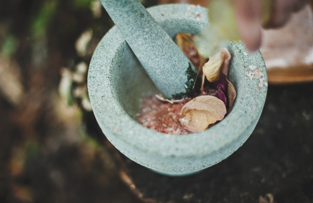 A stone mortar half full of coarsely crushed spices with the pestle resting inside